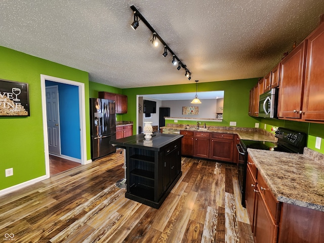 kitchen featuring black appliances, decorative light fixtures, a textured ceiling, dark hardwood / wood-style flooring, and a center island