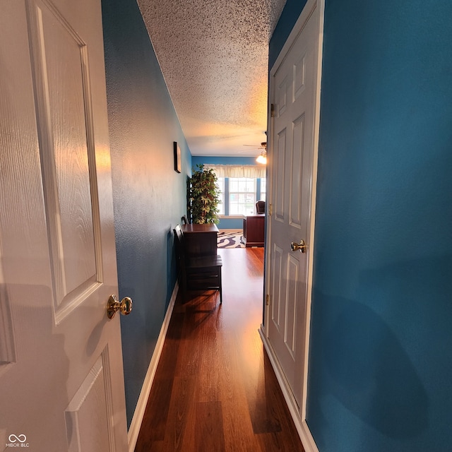 corridor with dark hardwood / wood-style floors and a textured ceiling