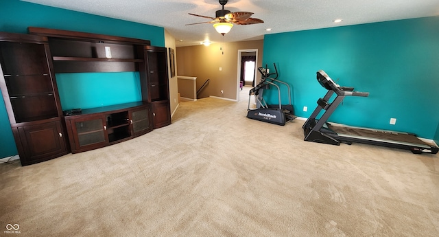 workout area with a textured ceiling, light colored carpet, and ceiling fan