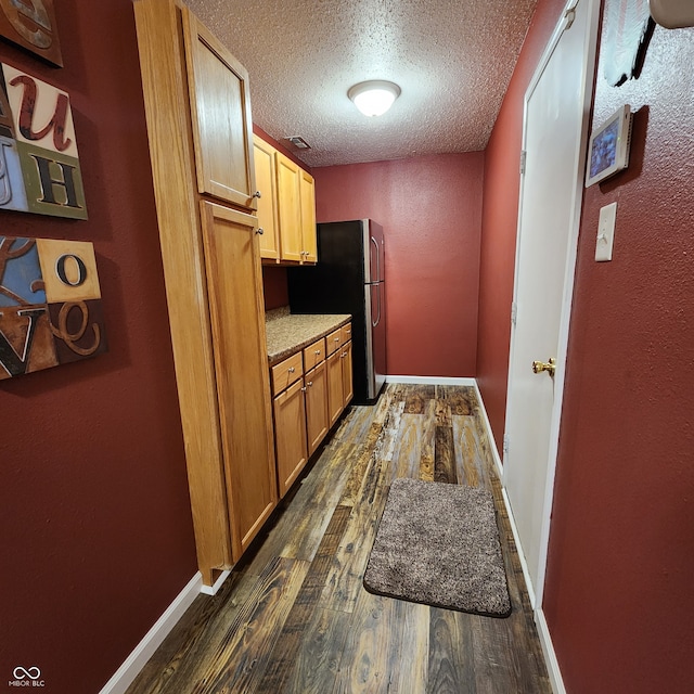 kitchen featuring dark hardwood / wood-style flooring, a textured ceiling, and stainless steel fridge