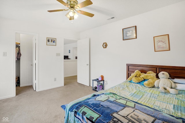 carpeted bedroom with a spacious closet, ceiling fan, and a closet