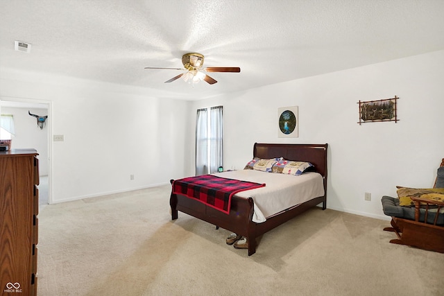 bedroom featuring ceiling fan, a textured ceiling, and light carpet