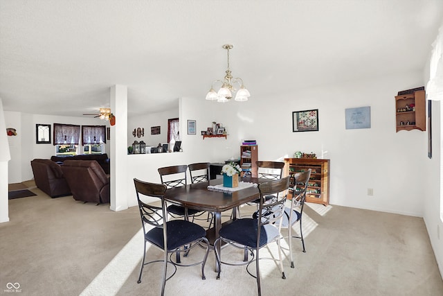 carpeted dining area with ceiling fan with notable chandelier