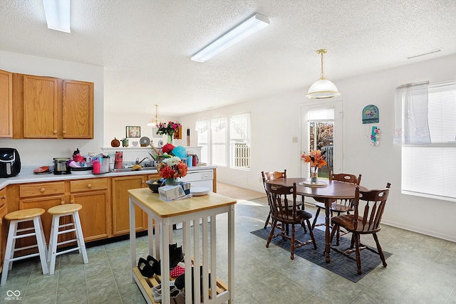 kitchen with sink, hanging light fixtures, and a textured ceiling