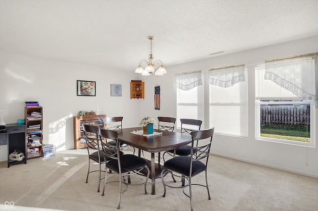 dining room with a textured ceiling, light carpet, and a notable chandelier