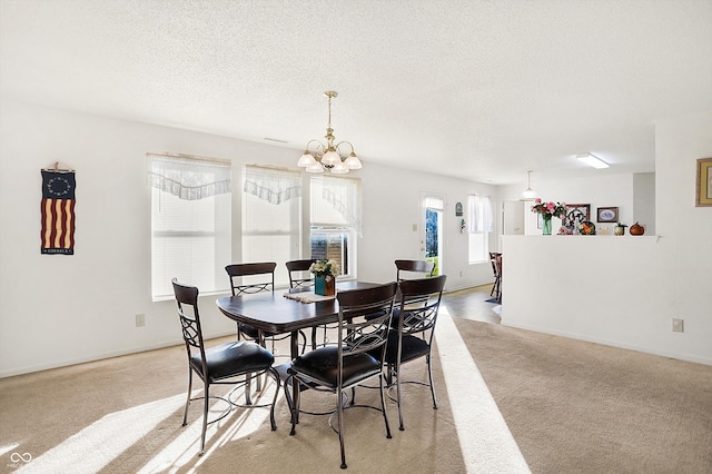 dining area featuring a chandelier, a textured ceiling, and light carpet