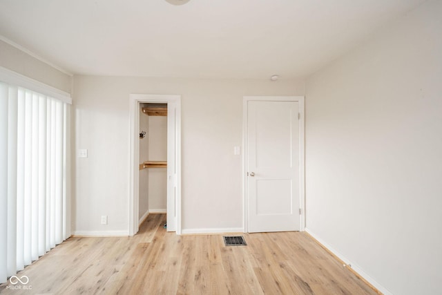 unfurnished bedroom with a spacious closet, a closet, and light wood-type flooring