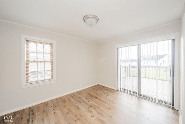 spare room featuring crown molding, plenty of natural light, and light wood-type flooring