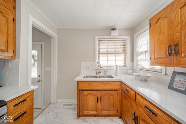 kitchen with sink, decorative backsplash, and light stone countertops