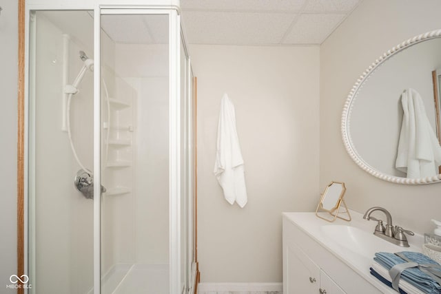 bathroom featuring a paneled ceiling, vanity, and an enclosed shower