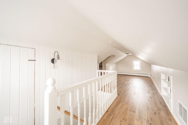 bonus room with lofted ceiling, light hardwood / wood-style floors, and a baseboard heating unit