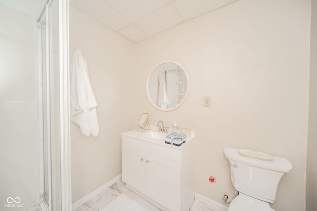 bathroom with a drop ceiling, vanity, and toilet