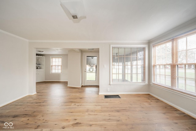 empty room with crown molding and light wood-type flooring