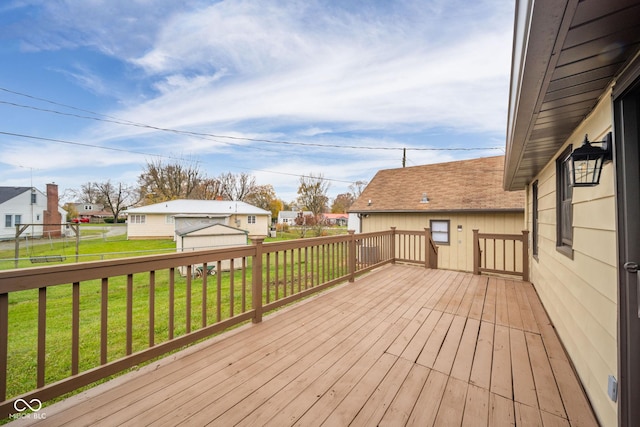 wooden terrace featuring a garage, a lawn, and an outdoor structure