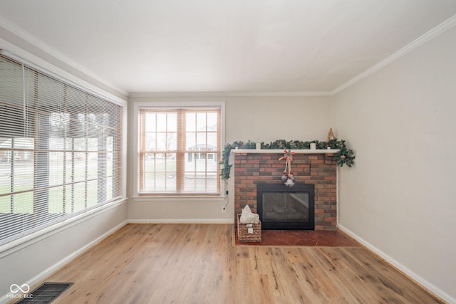 living room with a brick fireplace, ornamental molding, and light wood-type flooring