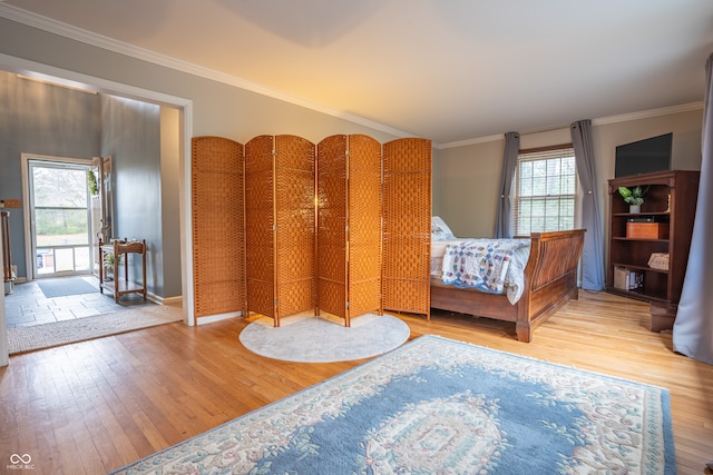 bedroom with multiple windows, light hardwood / wood-style flooring, and crown molding