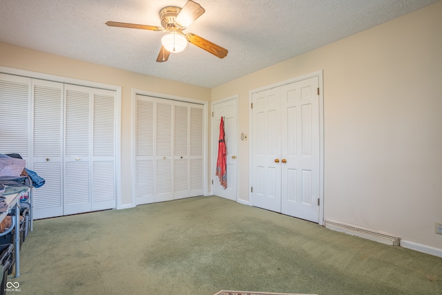 unfurnished bedroom with a textured ceiling, carpet flooring, a baseboard heating unit, two closets, and ceiling fan