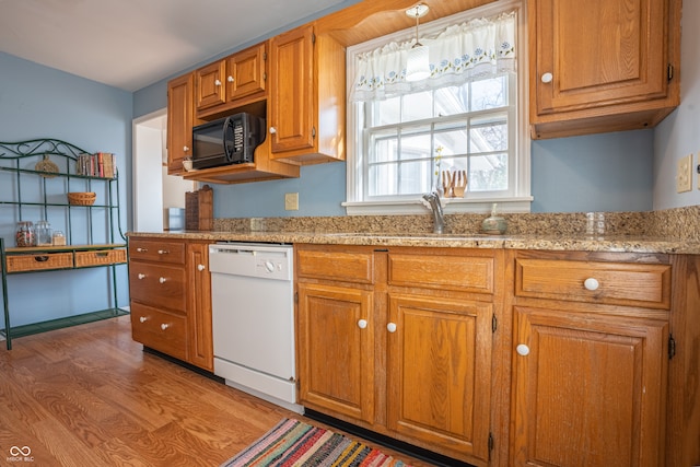 kitchen with white dishwasher, light stone countertops, pendant lighting, sink, and hardwood / wood-style floors