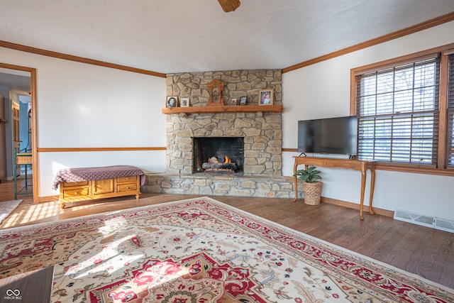 living room with ornamental molding, a fireplace, a textured ceiling, and hardwood / wood-style flooring