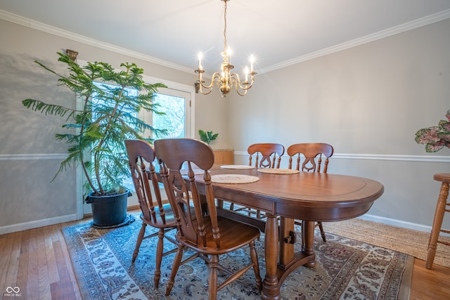 dining area with hardwood / wood-style floors, a notable chandelier, and ornamental molding