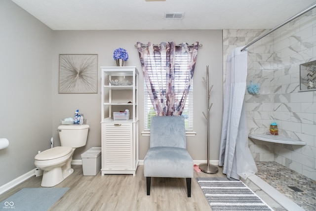 bathroom featuring a shower with shower curtain, wood-type flooring, and toilet