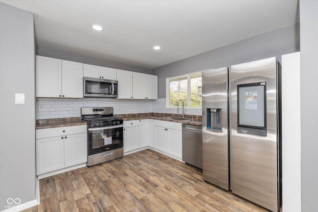 kitchen featuring sink, white cabinetry, appliances with stainless steel finishes, and wood-type flooring