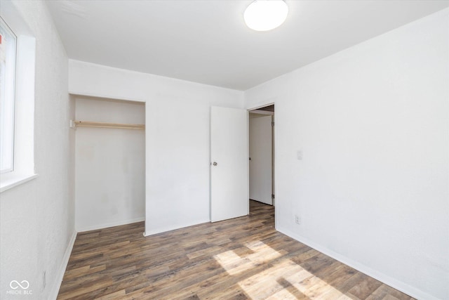 unfurnished bedroom with dark hardwood / wood-style floors and a closet