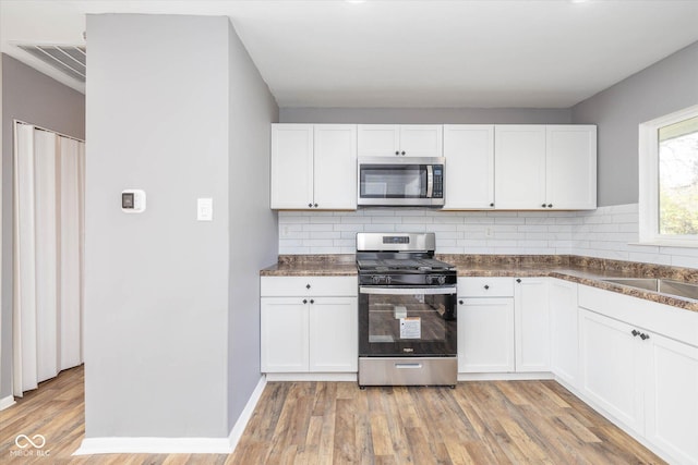 kitchen with stainless steel appliances, white cabinets, and light hardwood / wood-style flooring