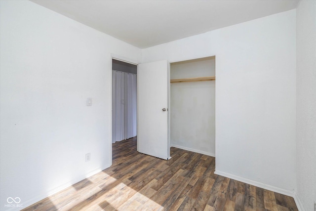 unfurnished bedroom with dark wood-type flooring and a closet