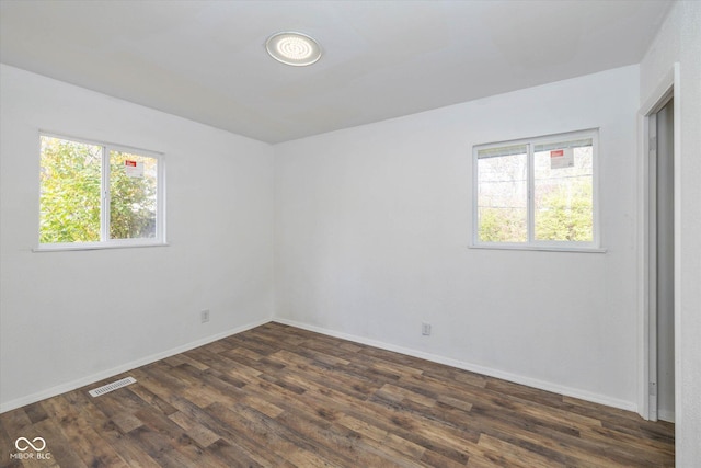 empty room featuring a healthy amount of sunlight and dark hardwood / wood-style floors