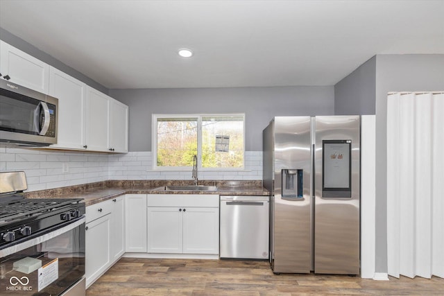 kitchen with stainless steel appliances, light hardwood / wood-style floors, white cabinetry, and sink