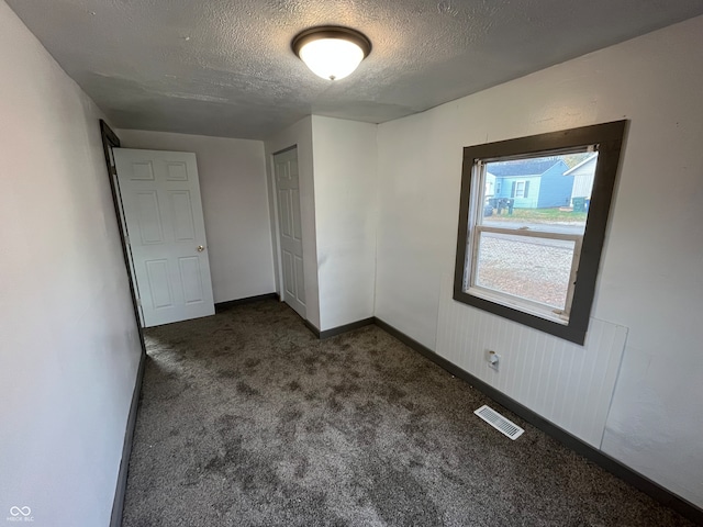 carpeted empty room featuring a textured ceiling