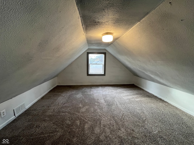 additional living space featuring a textured ceiling, vaulted ceiling, and carpet floors