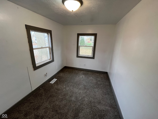 carpeted empty room featuring a textured ceiling