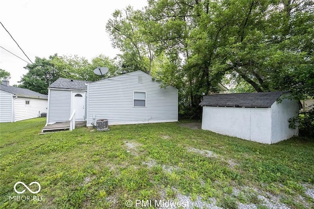 back of house featuring cooling unit, a storage unit, and a yard