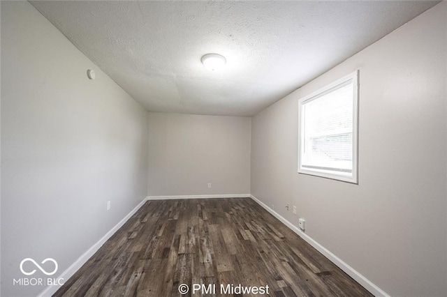 unfurnished room featuring a textured ceiling and dark hardwood / wood-style floors