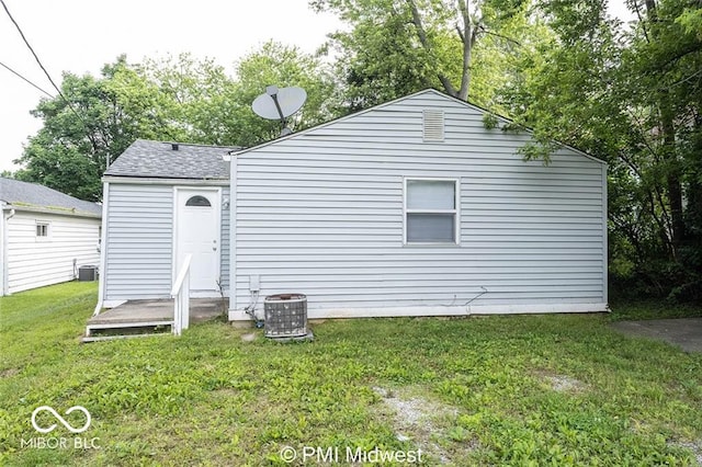 rear view of property with central AC unit and a yard