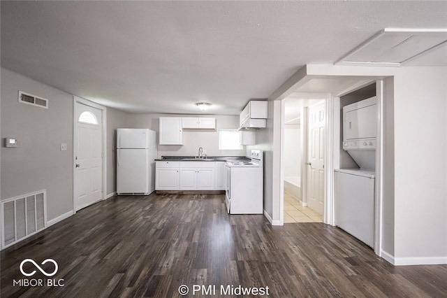 kitchen featuring stacked washer and clothes dryer, dark hardwood / wood-style flooring, sink, white cabinets, and white appliances