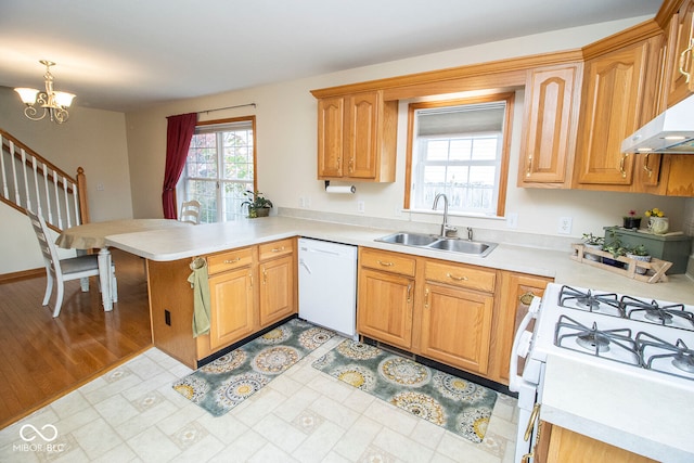 kitchen with kitchen peninsula, white appliances, sink, a chandelier, and light hardwood / wood-style floors