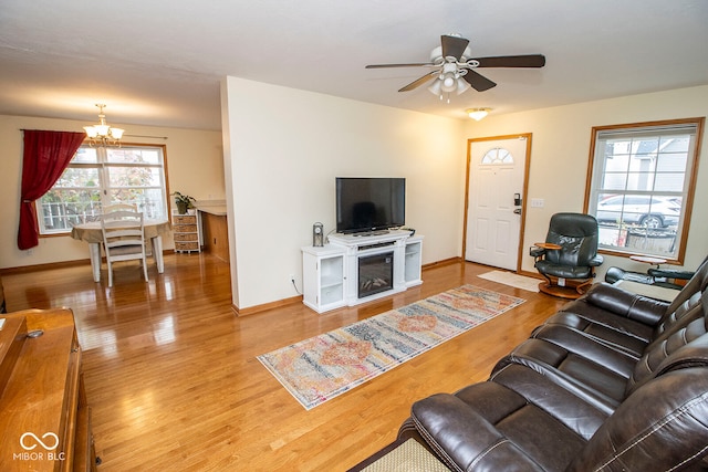 living room featuring plenty of natural light, wood-type flooring, and ceiling fan with notable chandelier