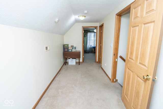 hall with a textured ceiling, lofted ceiling, and light carpet