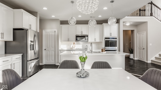 kitchen featuring appliances with stainless steel finishes, a kitchen breakfast bar, dark wood-type flooring, decorative light fixtures, and white cabinets