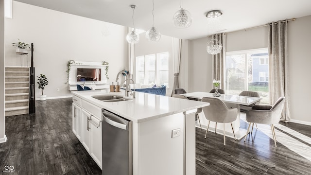 kitchen featuring dark hardwood / wood-style flooring, stainless steel dishwasher, sink, pendant lighting, and a center island with sink