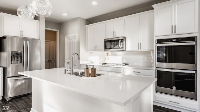 kitchen with white cabinets, an island with sink, decorative light fixtures, and appliances with stainless steel finishes