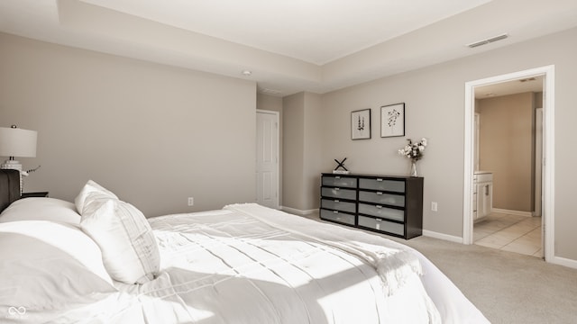 bedroom featuring light carpet, connected bathroom, and a closet