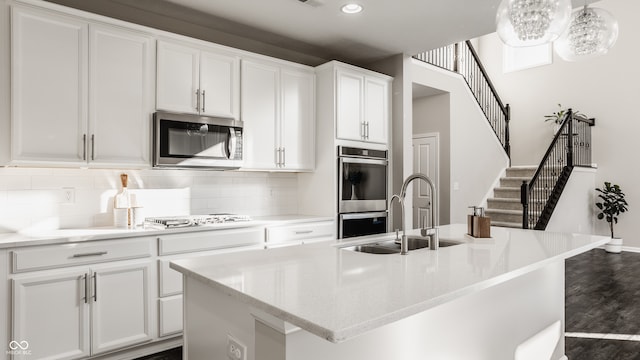 kitchen with a kitchen island with sink, dark hardwood / wood-style flooring, white cabinets, and appliances with stainless steel finishes