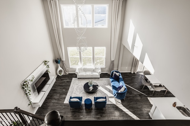 living room with plenty of natural light, dark wood-type flooring, and an inviting chandelier