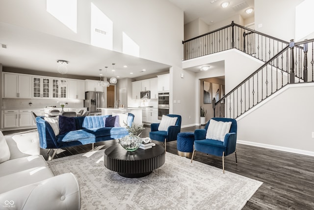 living room featuring hardwood / wood-style floors, a notable chandelier, sink, and a high ceiling