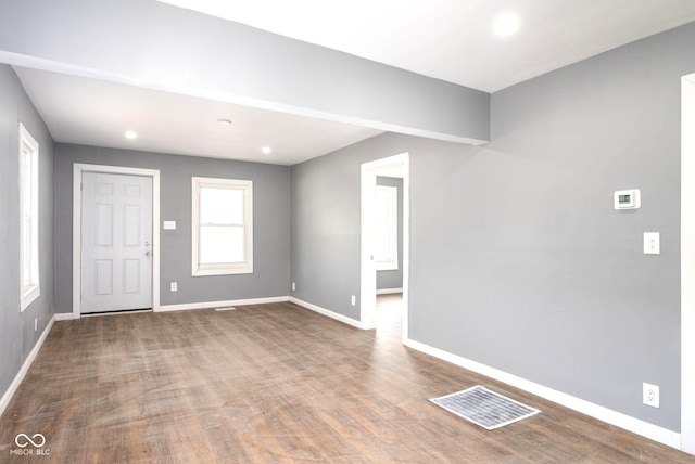 unfurnished room with wood finished floors, visible vents, and baseboards