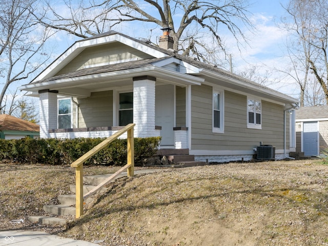 bungalow with cooling unit, covered porch, and a chimney